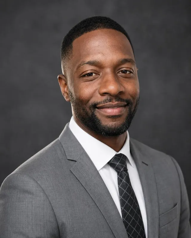 AI realtor headshot: man in a grey suit and tie against a dark studio backdrop